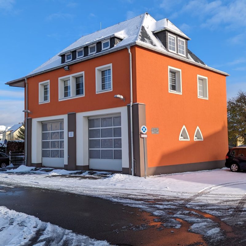Gebäude mit orangefarbener Fassade und Garagentoren im Winter