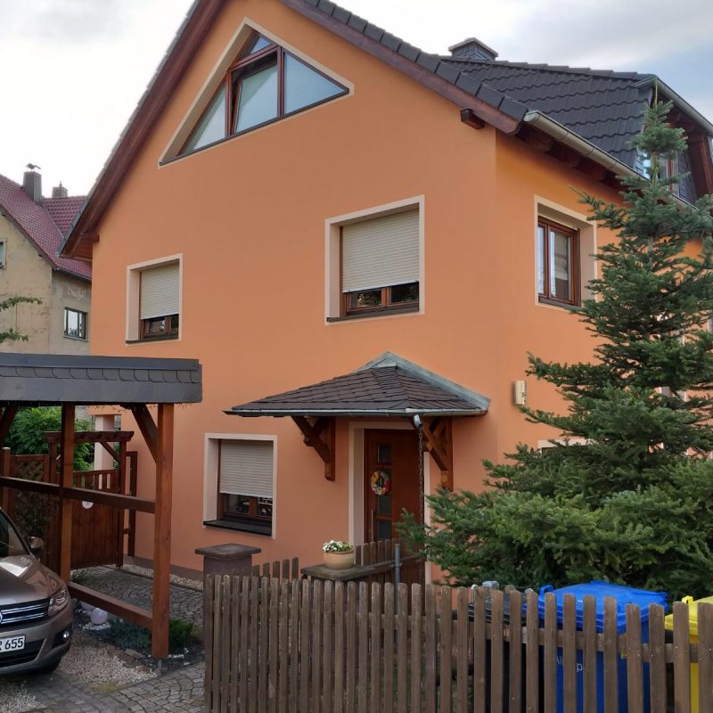 Einfamilienhaus mit orangefarbener Fassade und Carport