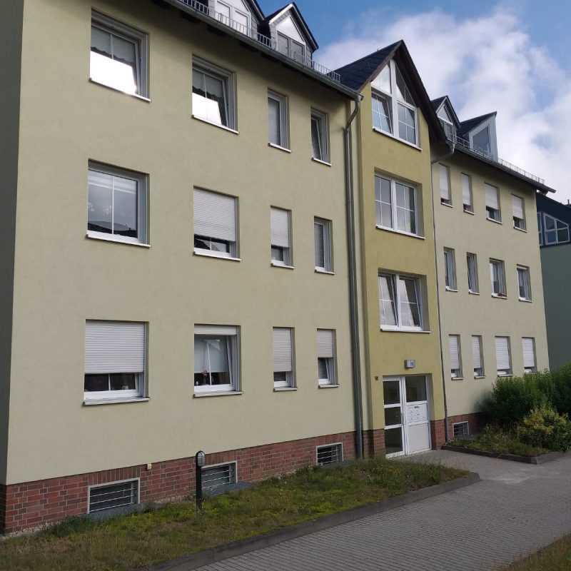 Mehrfamilienhaus mit beiger Fassade und Dachgauben