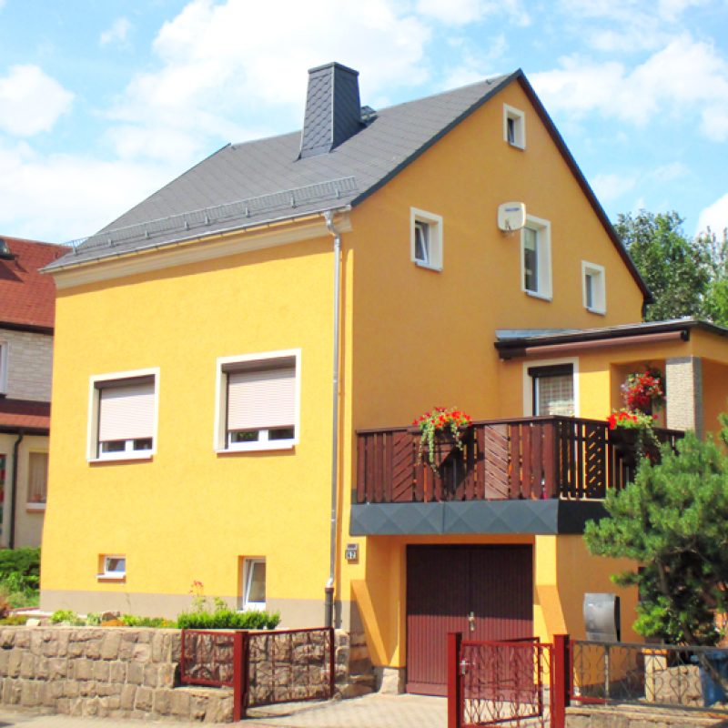 Einfamilienhaus mit gelber Fassade und Balkon