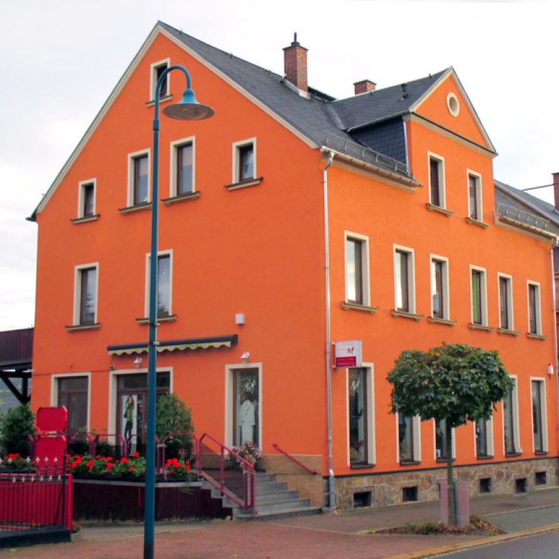Wohn- und Geschäftshaus mit orangefarbener Fassade an einer Straße
