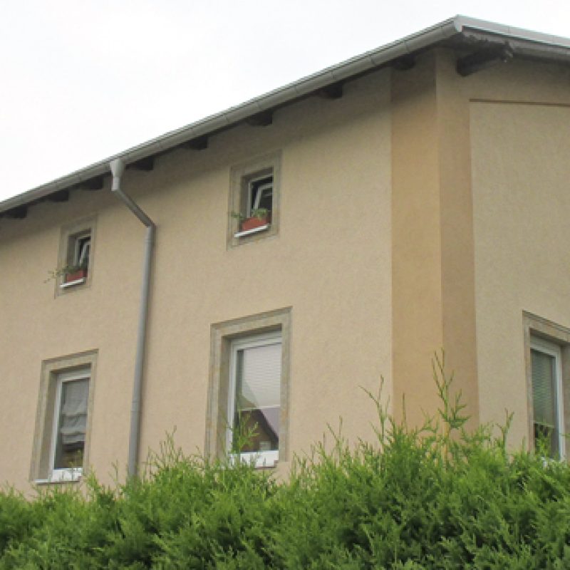 Wohnhaus mit beiger Fassade und hellen Faschen