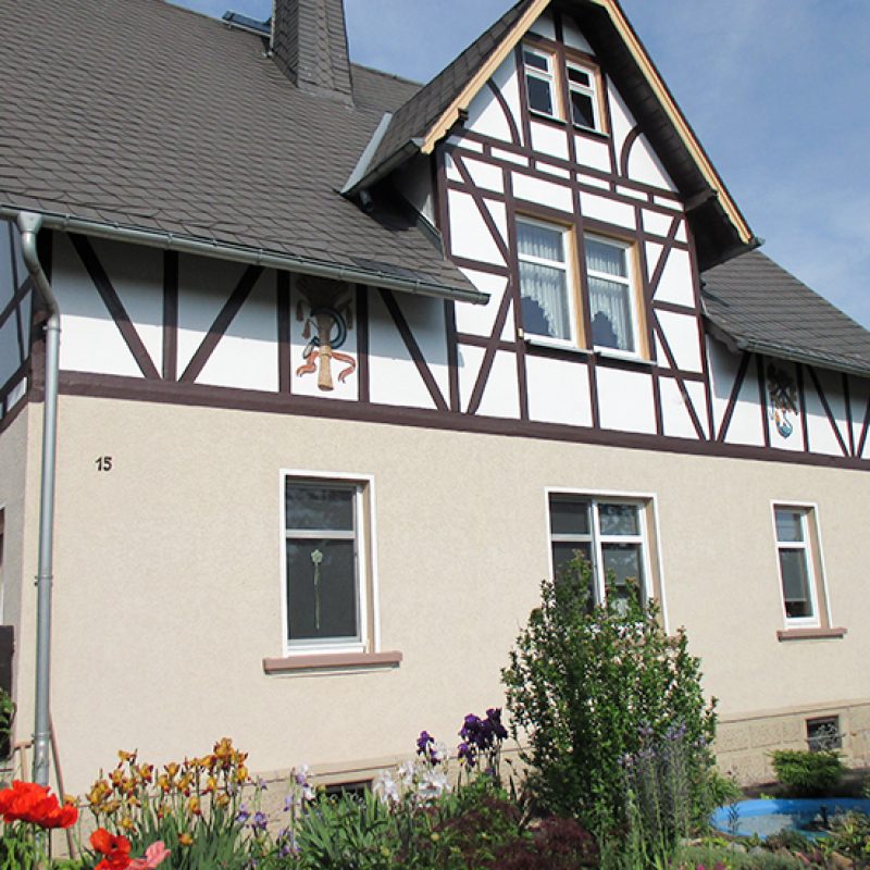 Fachwerkhaus mit hellem Putz und Blumenbeet