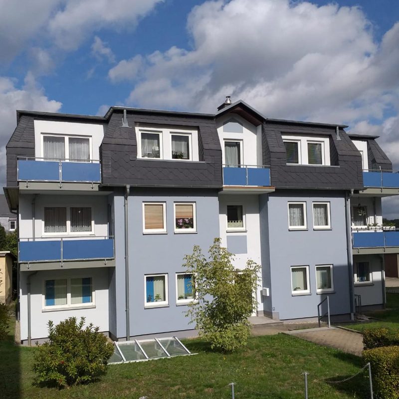 Mehrfamilienhaus mit hellblauer Fassade und Balkonen