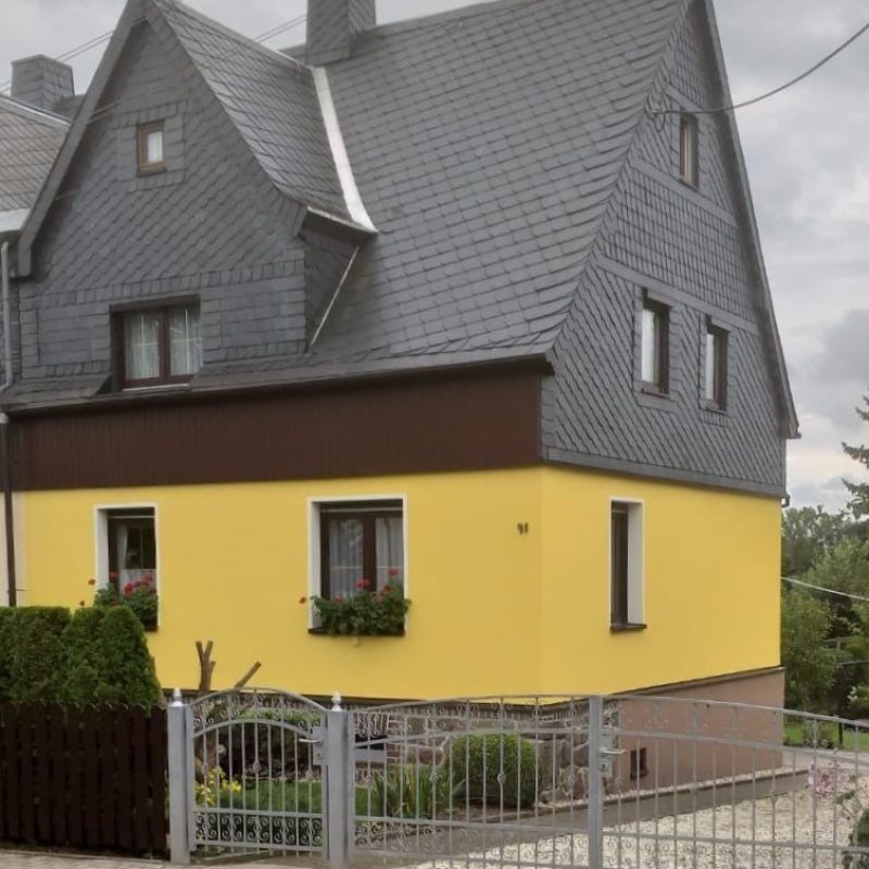 Wohnhaus mit gelb gestrichenem Erdgeschoss und Schieferdach